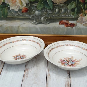 May include: Two white oval serving bowls with a gold rim and a floral design in shades of pink, blue, and brown.