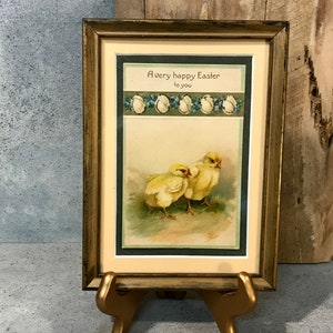 May include: A framed vintage Easter card with a gold frame and a green mat. The card features a watercolor illustration of two yellow chicks with the text "A very happy Easter to you".