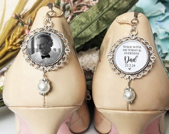 May include: A pair of beige high heels with decorative charms. One charm features a black and white photo of a man, the other has the text "Walk with me today & everyday Dad 22.2.24". Each charm has a dangling pearl.