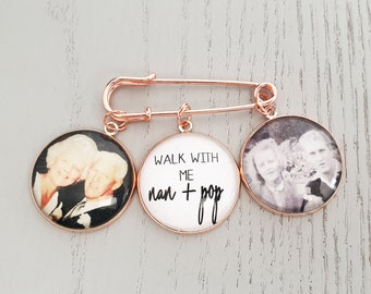 May include: A rose gold brooch with three circular pendants. Two pendants feature black and white photos of people, and the center pendant has the text "WALK WITH ME nan + pop" in black script.