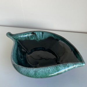 May include: A green and black ceramic leaf-shaped serving bowl. The bowl has a glossy finish and a deep, rounded interior.