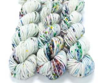 May include: Three skeins of white yarn with colorful speckles. The yarn is arranged in a square shape.