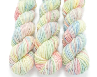 May include: Three skeins of yarn in a pastel colorway with shades of pink, blue, green, and yellow.