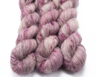 May include: Three skeins of yarn in a soft pink and gray colorway. The yarn is a blend of mohair and silk, and has a fuzzy, textured appearance.