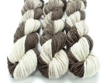 May include: Three skeins of yarn in a brown and white colorway. The yarn is thick and fluffy, and it is perfect for knitting or crocheting.