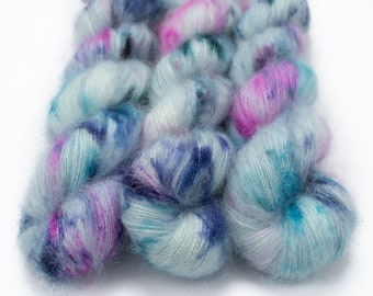 May include: A skein of hand-dyed yarn in shades of blue, teal, pink, and white. The yarn is soft and fluffy, with a subtle shimmer.