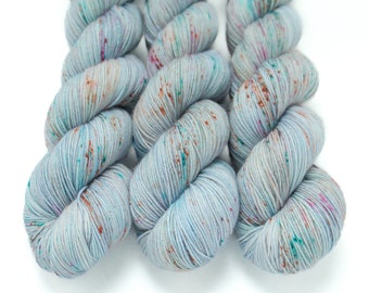 May include: Three skeins of yarn in a light blue colour with speckles of teal, pink, and orange.