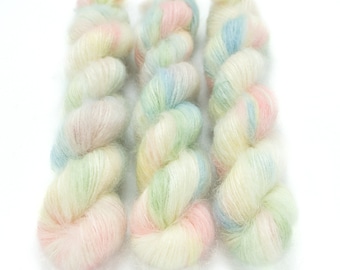 May include: Three skeins of yarn in a pastel color palette. The yarn is a blend of white, pink, blue, and green.