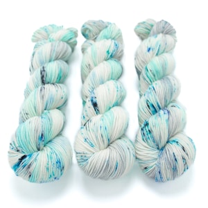 May include: Three skeins of yarn in a white base with blue, teal, and gray speckles.
