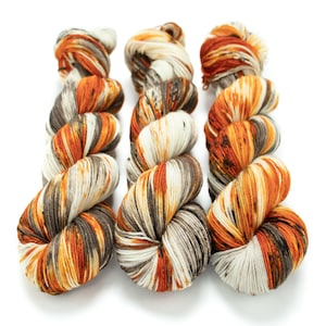 May include: Three skeins of yarn in a variegated pattern of orange, brown, and white.