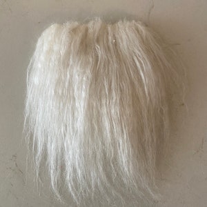 May include: A white fluffy beard made of faux fur. The beard is long and full, with a natural-looking texture.