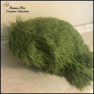 May include: A green fluffy fabric backdrop for newborn photography. The fabric is soft and plush, perfect for creating a cozy and comfortable setting for baby photos.