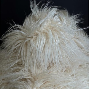 Könnte beinhalten: Nahaufnahme eines flauschigen, weißen Kunstpelzes. Das Fell ist weich und plüschig mit einem langen Flor.
