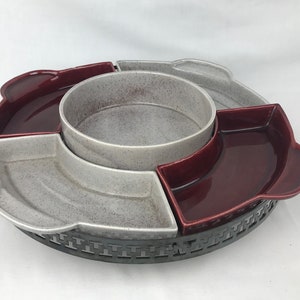 May include: A ceramic serving dish with a metal base. The dish has four sections, two are red and two are gray. The dish is perfect for serving snacks or appetizers.