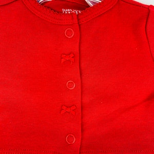 May include: Red ribbed cardigan with a white and pink heart print skirt. The cardigan has a scalloped neckline and four buttons with bows. The text "Just One You" is visible on the tag.
