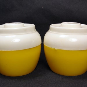 May include: Two yellow and white ceramic salt and pepper shakers. The shakers are round and have a smooth, glossy finish.