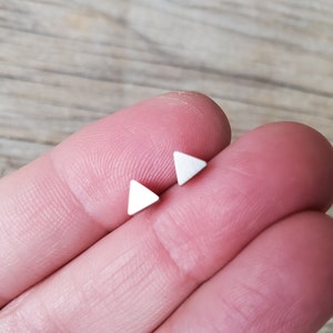 May include: A pair of silver triangle stud earrings.