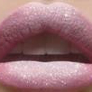 Puede incluir: Primer plano de labios rosados con un acabado brillante y brillante. Los labios son llenos y carnosos, con un ligero efecto degradado de un rosa más oscuro en los bordes a un rosa más claro en el centro.