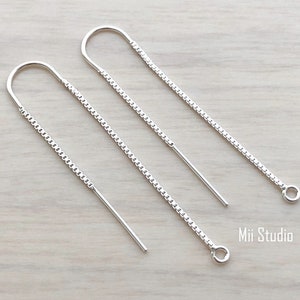 May include: Two silver chain earrings with a loop at the end of each chain. The chains are about 2 inches long.