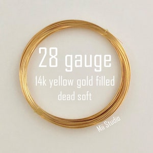 May include: A coil of 28 gauge, 14k yellow gold filled wire, labeled "dead soft". The wire is a bright, warm gold color, tightly wound in a circular shape. The text "Mii Studio" is in the bottom right corner.