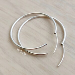 May include: A pair of silver hoop earrings. The hoops are open and ready to be worn.