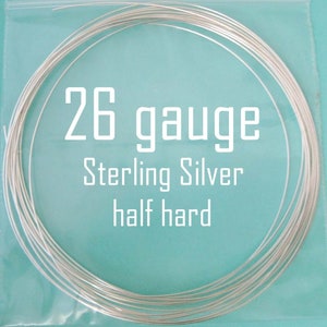 May include: A roll of 26 gauge sterling silver wire, half hard. The wire is silver in color and is wrapped around itself in a coil.