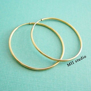 May include: A pair of gold hoop earrings. The earrings are simple and elegant, and they would be a great addition to any jewellery collection.