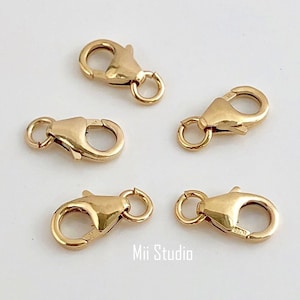 May include: Four gold-toned lobster clasps with a spring-loaded mechanism. The clasps are designed for attaching jewelry chains or cords.