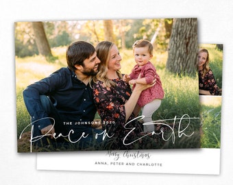 May include: A Christmas card template featuring a family of three, a couple and their young child, standing in a grassy field. The card has a white background with the text "Peace on Earth" in a handwritten font and "Merry Christmas" below it. The family's names are listed below the greeting. The card is 5 inches by 7 inches.