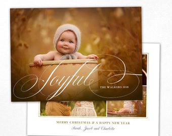 May include: Christmas card template, 5 x 7 inches, featuring a baby in a bonnet inside a wooden container. The word "Joyful" is written in elegant script. Additional photos and text are included, with the words "Merry Christmas & A Happy New Year".