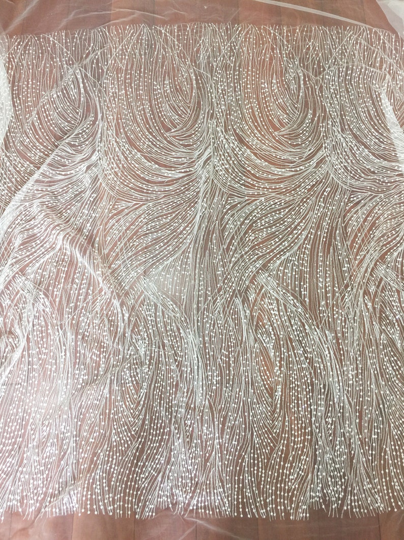 Peut inclure: Tissu blanc perl&eacute; avec un motif en spirale. Les perles sont petites et r&eacute;guli&egrave;rement espac&eacute;es, cr&eacute;ant un aspect d&eacute;licat et &eacute;l&eacute;gant.