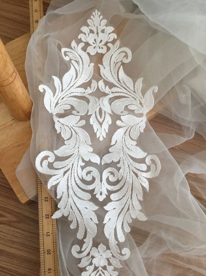 Puede incluir: Aplique de encaje blanco con un dise&ntilde;o floral. El aplique mide aproximadamente 23 pulgadas de largo y 8 pulgadas de ancho.