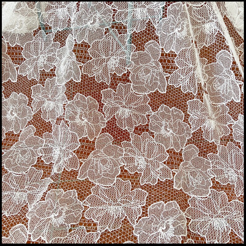 May include: White lace fabric with a floral pattern. The lace is delicate and intricate, with a fine mesh background.