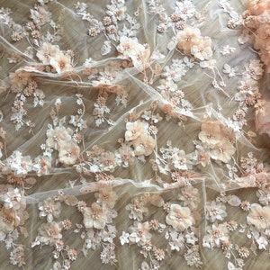 Puede incluir: Tela de encaje floral de color melocot&oacute;n con flores 3D y cuentas. La tela es transparente y delicada, con un borde festoneado.