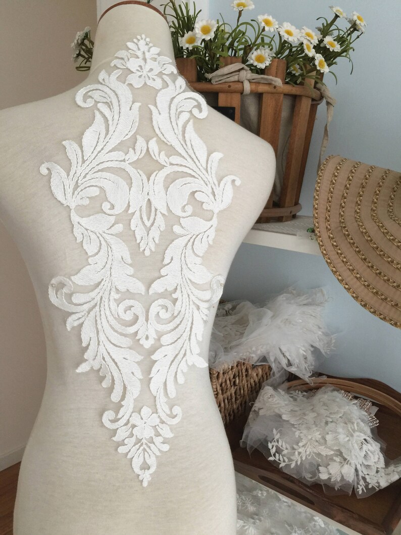Puede incluir: Aplique de encaje blanco con un dise&ntilde;o floral. El aplique est&aacute; en un maniqu&iacute; blanco y mide aproximadamente 45 cm de alto.