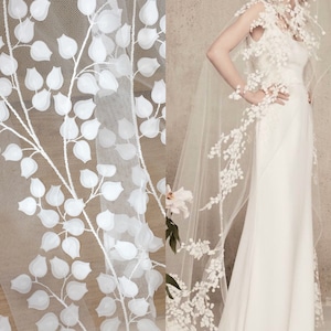 Peut inclure: Tulle blanc avec un motif floral délicat. Le tissu présente des feuilles et des branches en 3D, créant un look romantique et aérien.