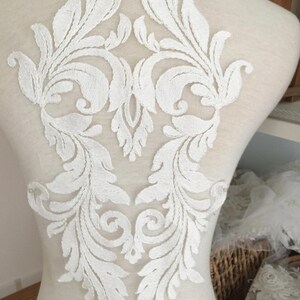 Puede incluir: Aplique de encaje blanco con un dise&ntilde;o floral. El aplique es perfecto para agregar un toque de elegancia a cualquier prenda.