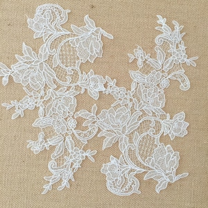 May include: White lace applique with a floral design. The lace is delicate and intricate, with a variety of flowers and leaves.