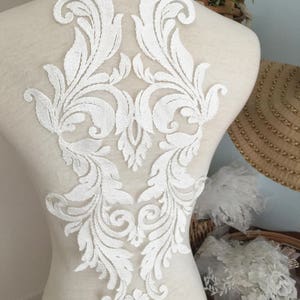 Puede incluir: Aplique de encaje blanco con un dise&ntilde;o floral. El aplique est&aacute; sobre un fondo blanco y es perfecto para agregar un toque de elegancia a cualquier proyecto.