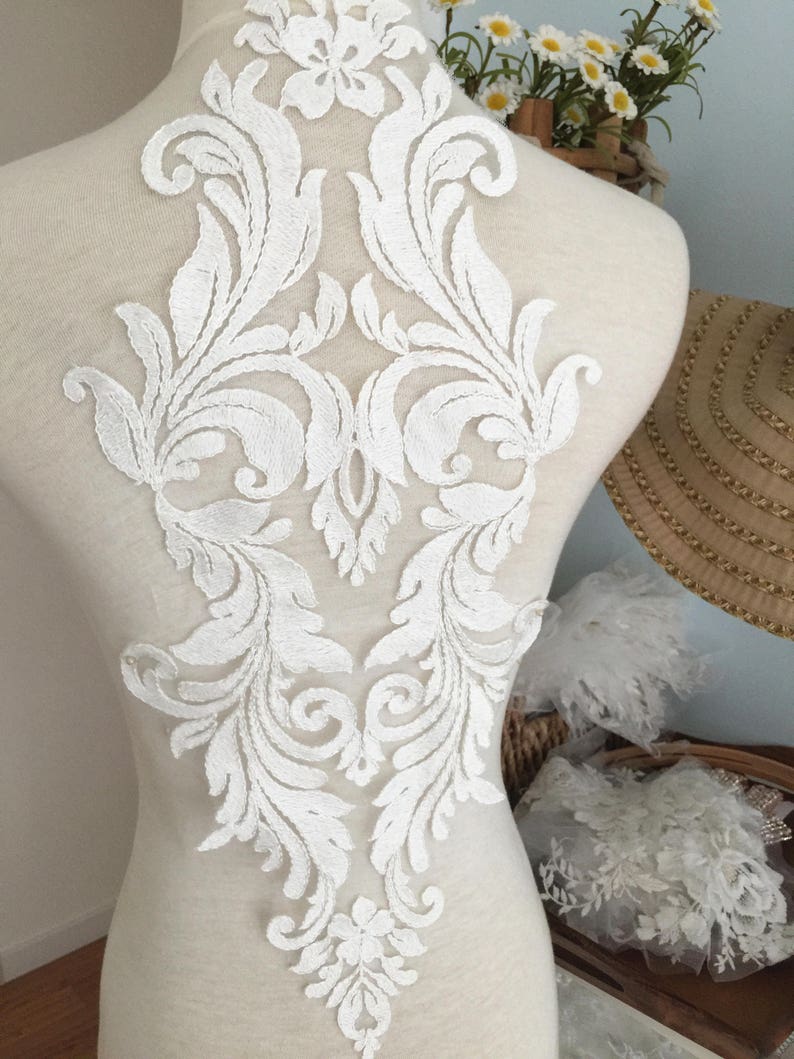 Puede incluir: Aplique de encaje blanco con un dise&ntilde;o floral. El aplique est&aacute; sobre un fondo blanco y es perfecto para agregar un toque de elegancia a cualquier proyecto.