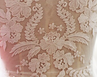 May include: White floral lace applique with delicate embroidery. The lace features a floral design with leaves and branches. This applique is perfect for adding a touch of elegance to any garment or project.