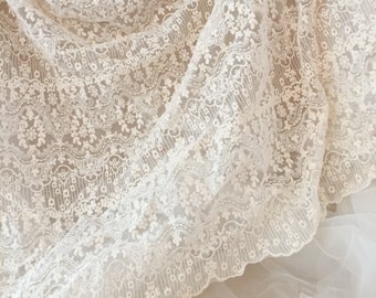 May include: White lace fabric with a delicate floral pattern. The lace has a scalloped edge and is soft and sheer.