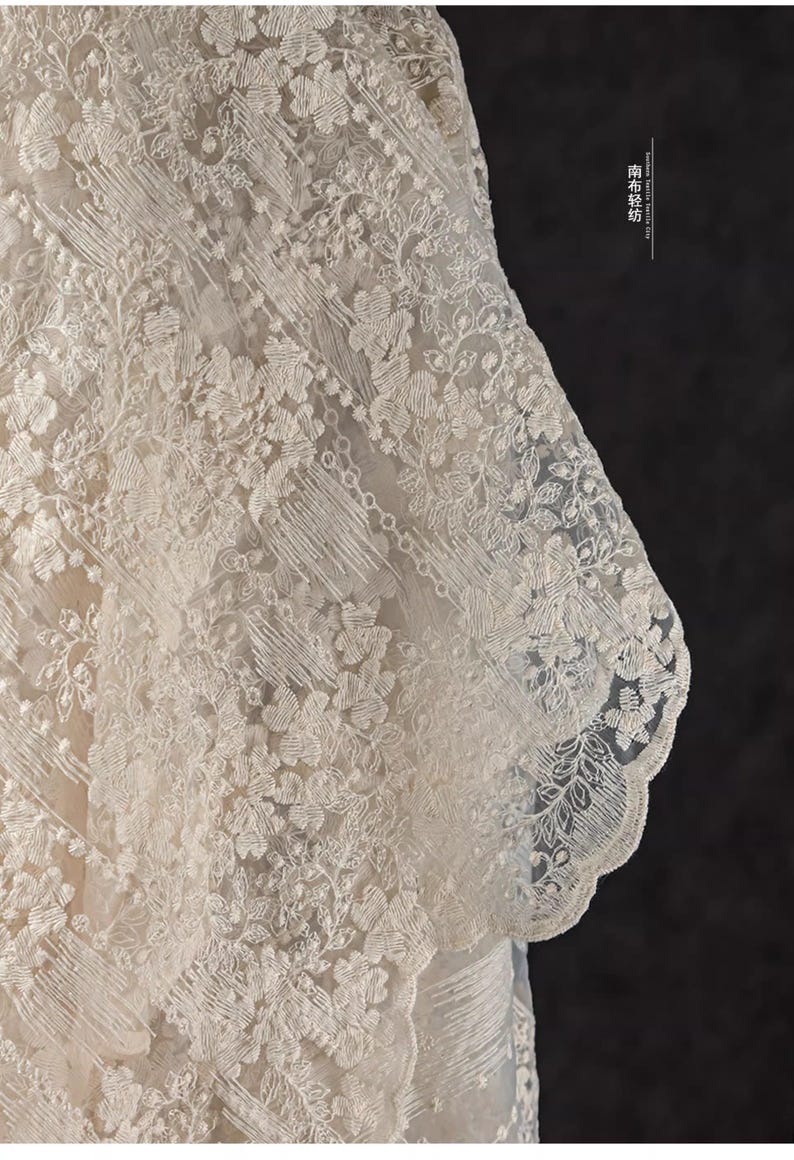 Peut inclure: Gros plan sur une dentelle d&eacute;licate de couleur blanc cass&eacute; avec un motif floral. La dentelle a un bord festonn&eacute; et une texture l&eacute;g&egrave;re et a&eacute;r&eacute;e.