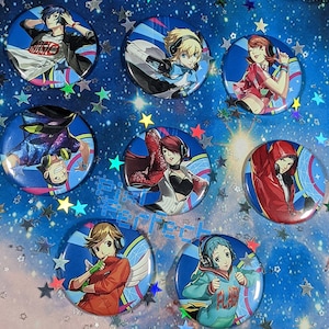 May include: Set of 8 colourful round pins featuring anime characters with headphones. The pins are decorated with a variety of designs, including geometric patterns, stars and musical notes.