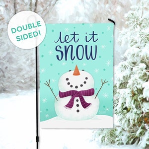 May include: A turquoise blue garden flag with a snowman wearing a purple scarf and the text "Let it snow".
