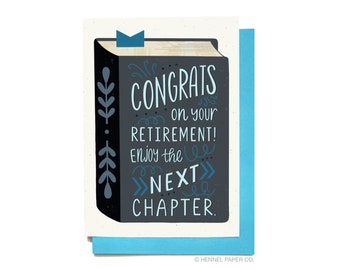 Puede incluir: Una tarjeta de felicitación con una ilustración de un libro negro. El libro tiene un marcapáginas azul y el texto "CONGRATS on your RETIREMENT! Enjoy the NEXT CHAPTER." en letras azules y blancas.
