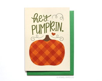 Puede incluir: Una tarjeta de felicitación con el texto "hey, pumpkin." La tarjeta presenta una calabaza de dibujos animados con un patrón de cuadros en tonos naranja y rojo.