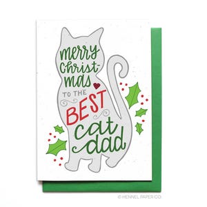 May include: A white Christmas card with a gray cat illustration. The card says "Merry Christmas to the Best Cat Dad" with green holly and red berries.