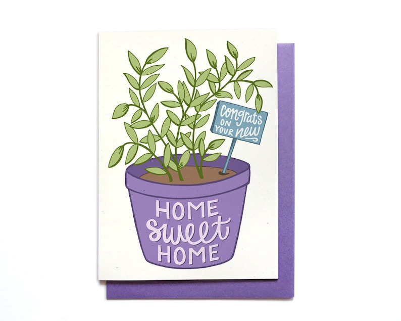 May include: A purple potted plant with green leaves and a blue sign that says "Congrats on your new home" and the text "Home sweet home" on the pot.