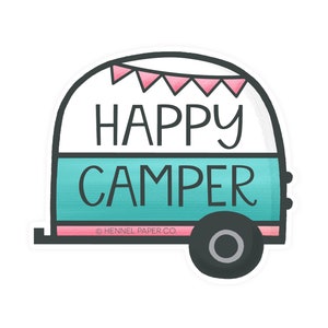 May include: A turquoise and pink camper van sticker with the text "HAPPY CAMPER" and a pink banner with flags on top. The sticker has a white background and black outlines. The text "© HENNEL PAPER CO." is at the bottom of the sticker.